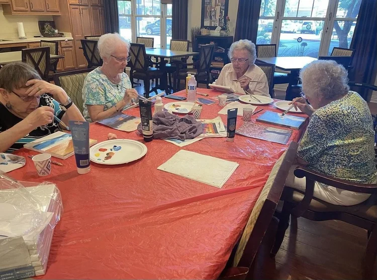 Older adults painting together around a table during an EaselArts session.